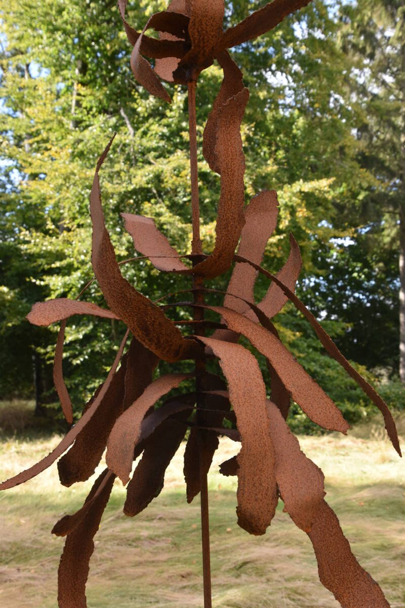 Jernskulptur med træ i baggrunden